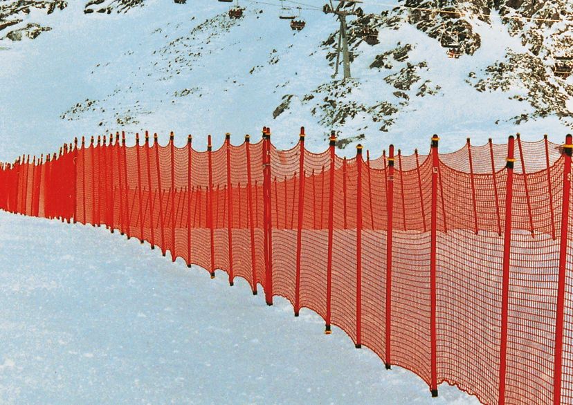 ski slope barrier net, orange, in snow