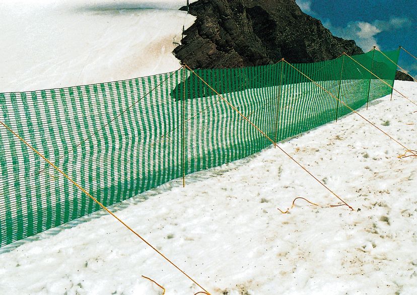 Schneefangzaun, grün, im Schnee mit Bergen im Hintergrund, Bild im Freien