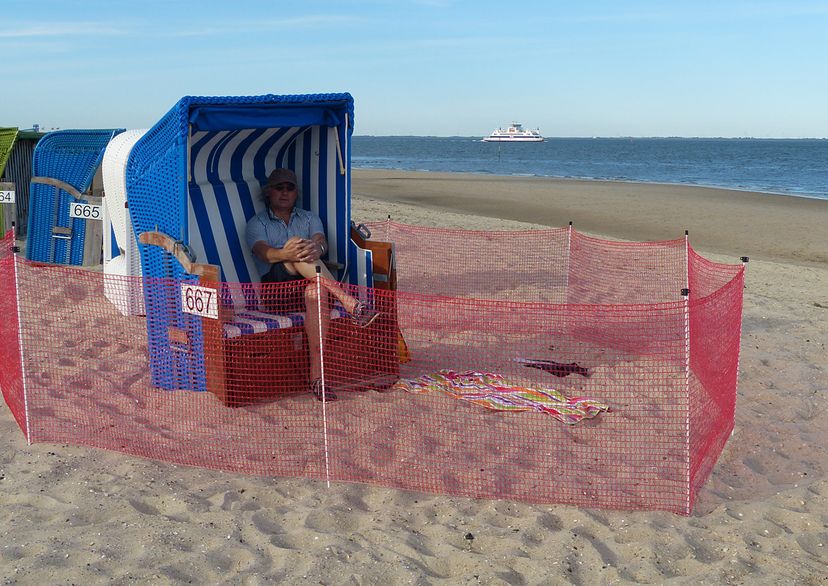 Red barrier fence on beach with beach-chair and ocean in the background