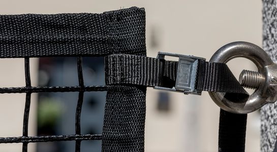 Area confinement net in black with buckled strap fastened to a screw bolted into a wal, detail picture