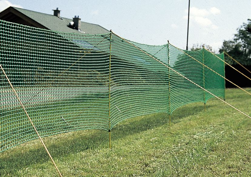Zaun, grün, auf Grass mit Haus im Hintergrund