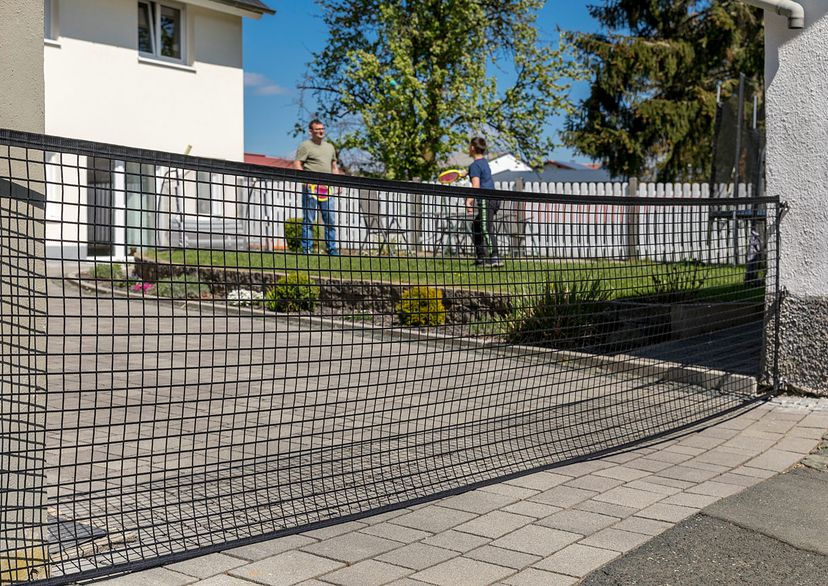 Area confinement net, between house and wall with 2 people playing in the garden