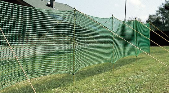 Fence, green, on gras with house in the background