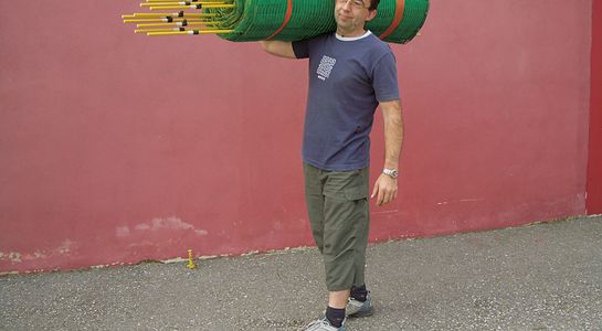 Man holds snow fence above shoulders, red background