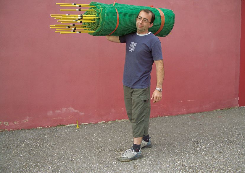 Man holds snow fence above shoulders, red background